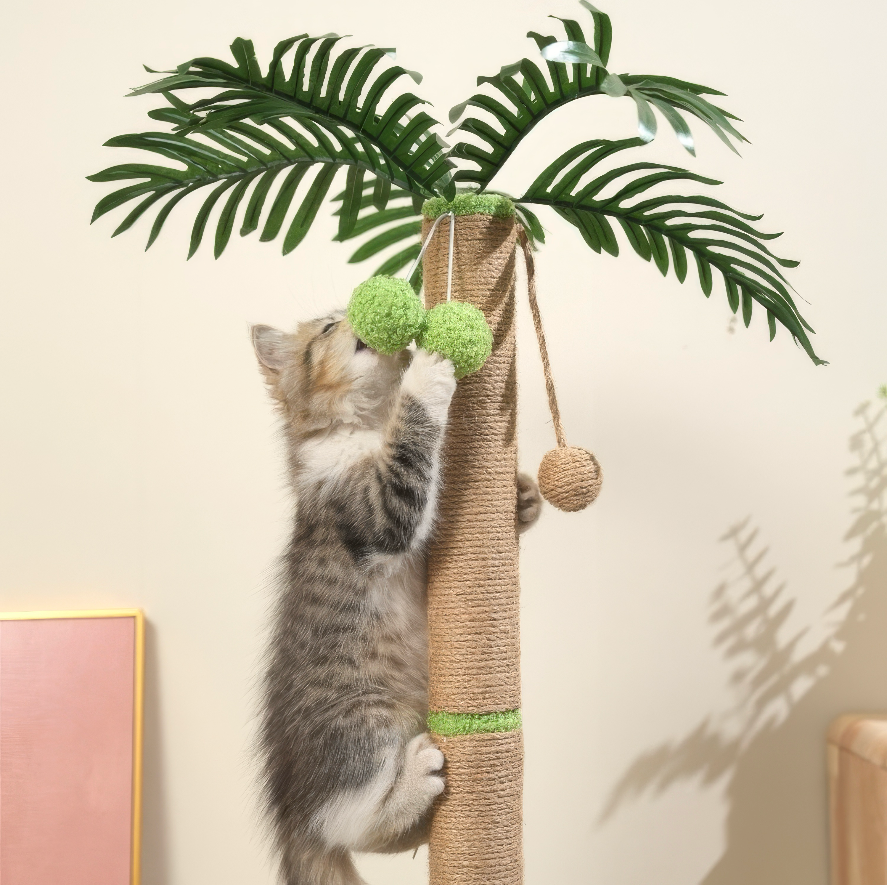 Kitten playing with a cat palm tree with green balls and leaves on a beige wall