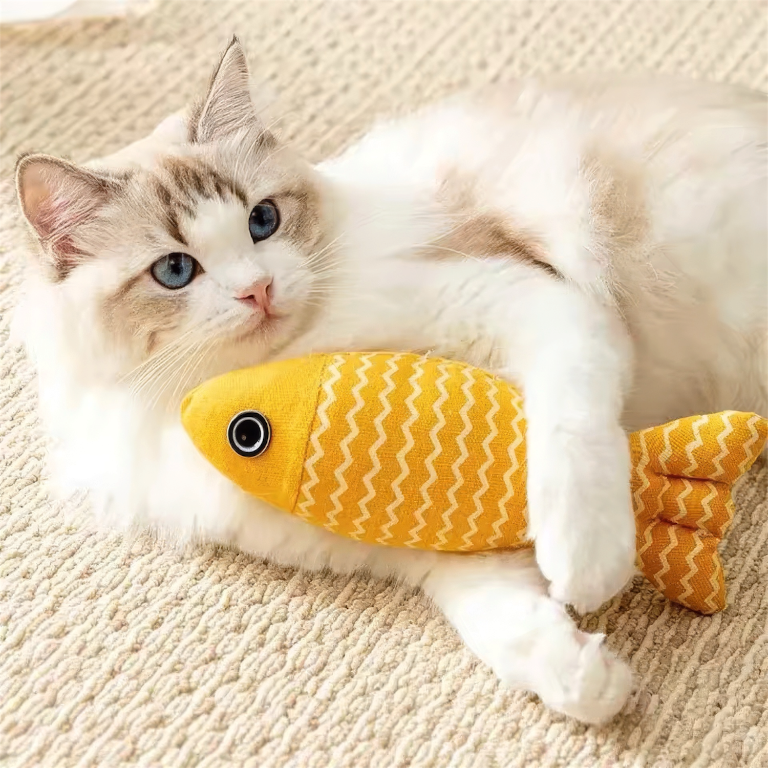 Cat playing with a yellow fish-shaped toy on a beige carpet